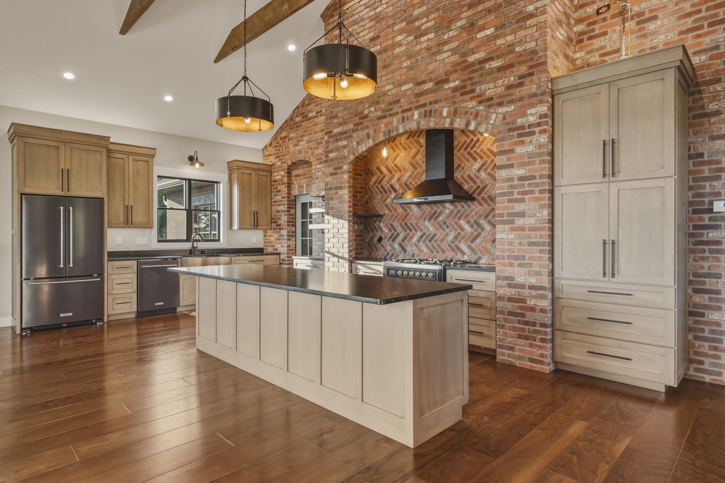 Kitchen with a brick arch range wall, oak cabinets and a long island